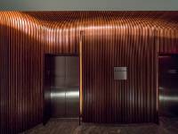 Light is used in slots next to the elevator doors. When the call button is pressed, light is used to signal the available elevator car. Pure Timber fabricated removable panels and recesses for the LED lighting